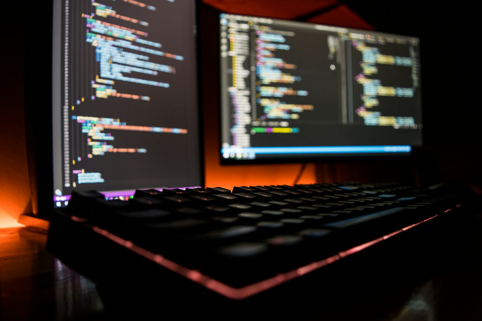 プログラミングコードが表示された2台のモニターとキーボード